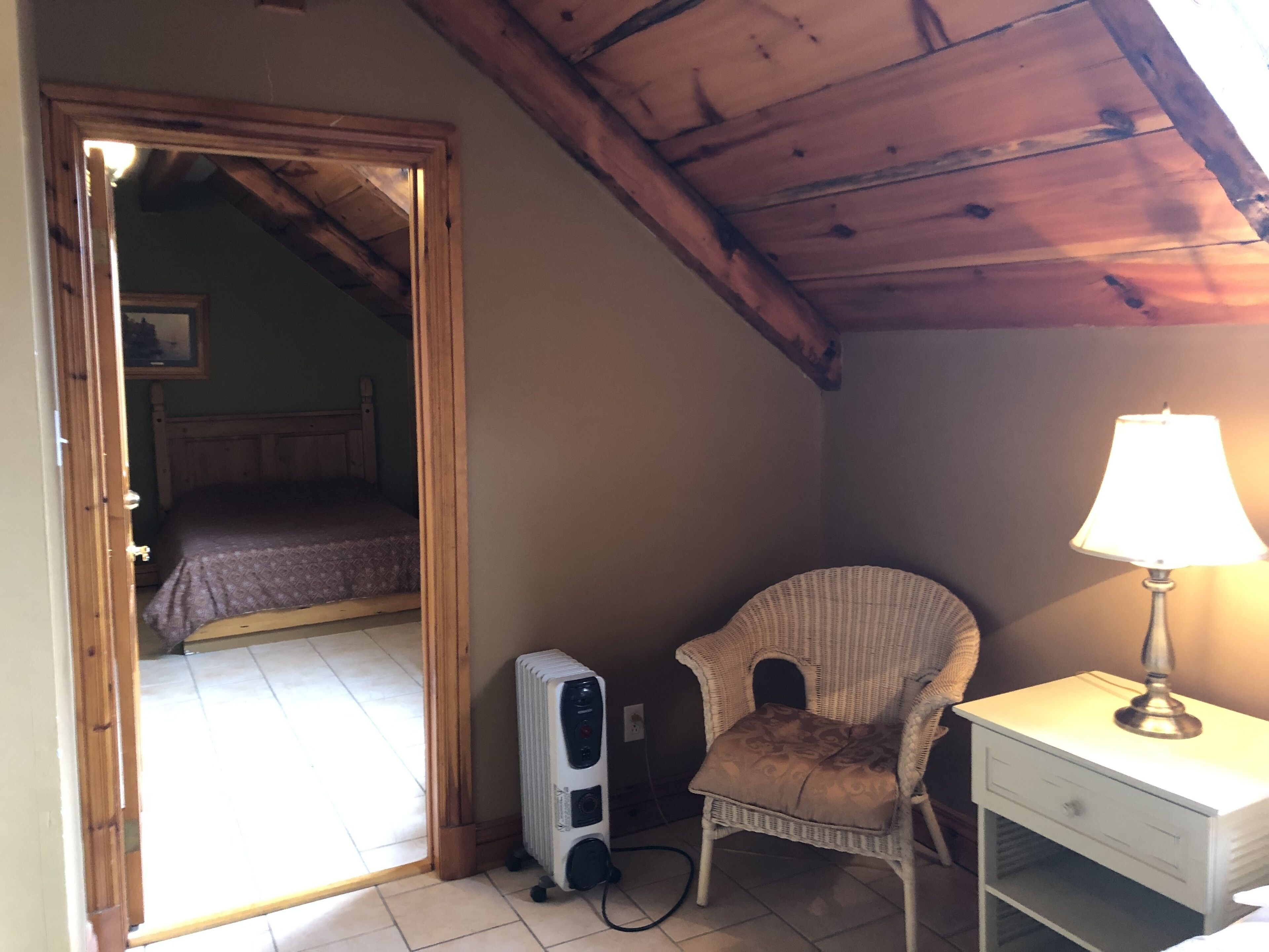 Une chambre à coucher avec un lit, une chaise, une table de chevet avec une lampe et un radiateur.