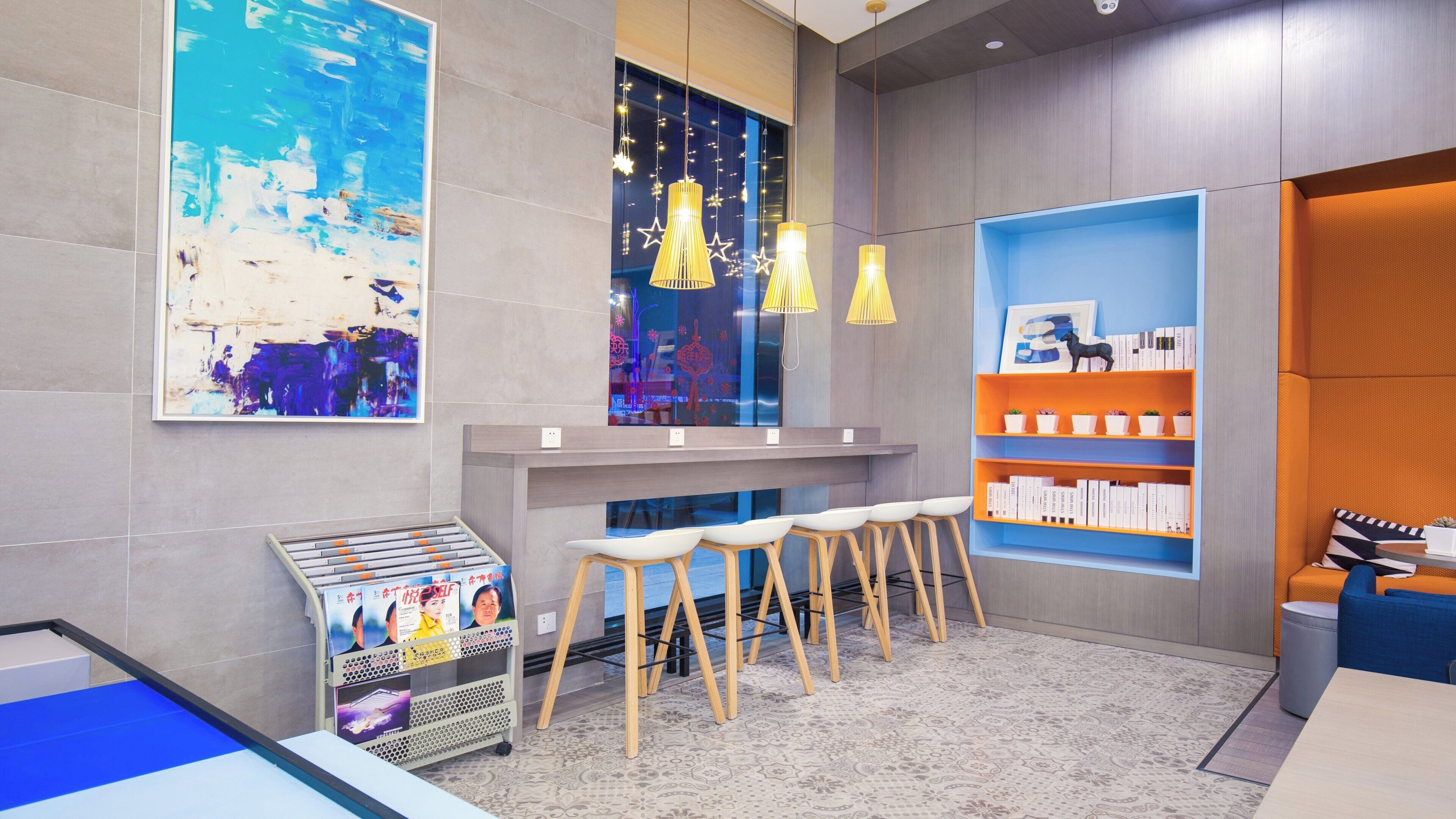 A modern bar area with a counter, bar stools, and a shelf with books and decorative items.