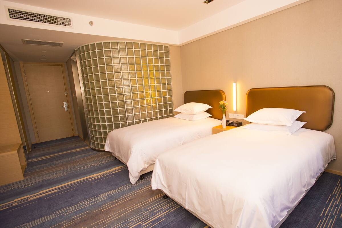 Ein Hotelzimmer mit zwei Betten, einem großen Fenster und Teppichboden.