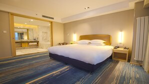A hotel room with a large bed, a bathroom with a marble vanity, and a view of the hallway.