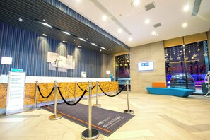 A hotel reception area with a modern design, featuring a reception desk, a waiting area with seating, and a glass wall displaying a festive interior. - Holiday Inn Express Chifeng Hongshan by IHG (Chifeng)