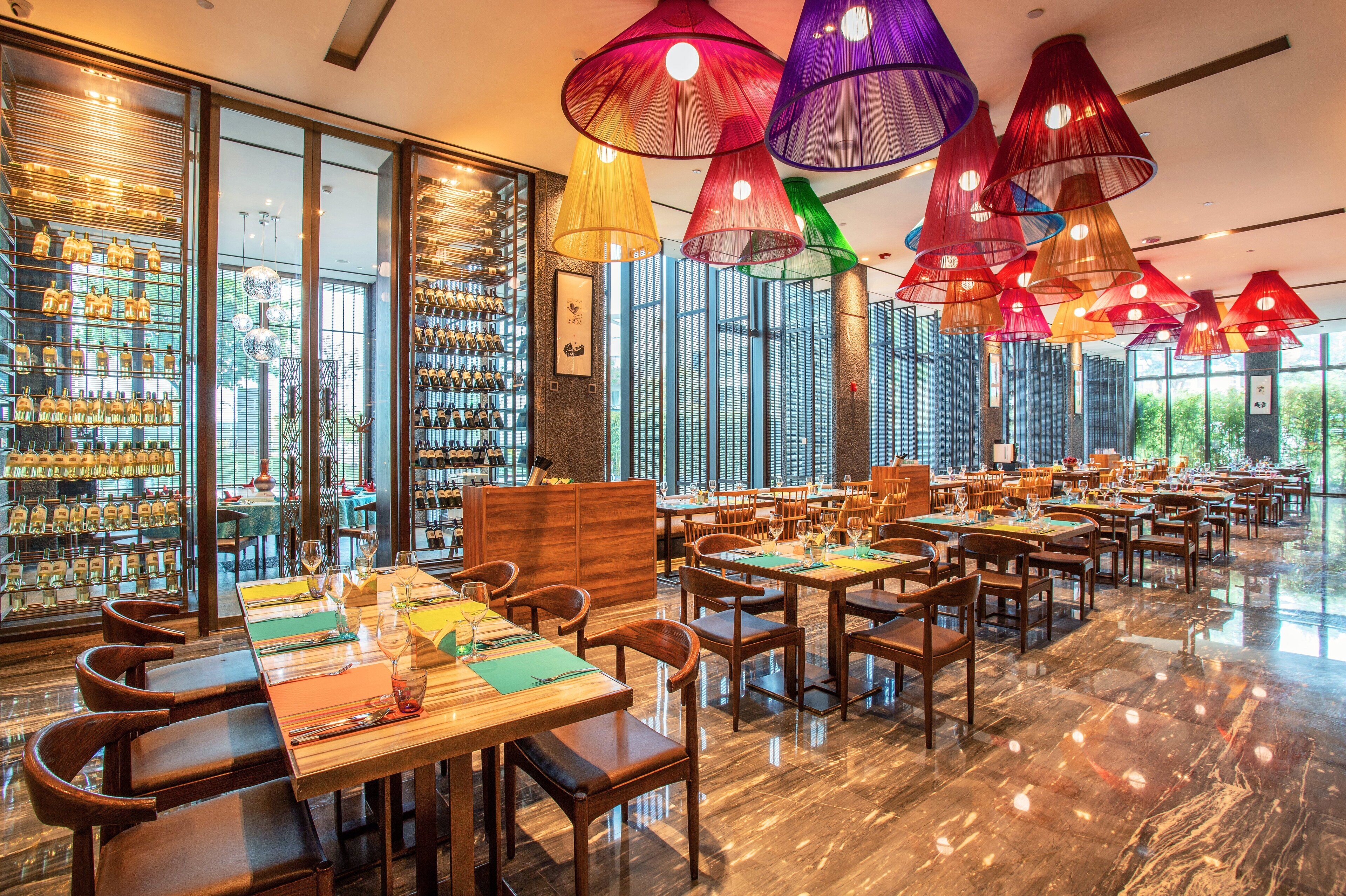 Un restaurante espacioso con techos altos, amplias ventanas y diferentes opciones de asientos.