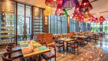 Un restaurante espacioso con techos altos, amplias ventanas y diferentes opciones de asientos.