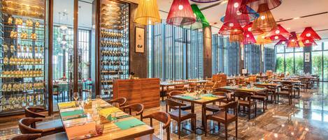 Un restaurante espacioso con techos altos, amplias ventanas y diferentes opciones de asientos.