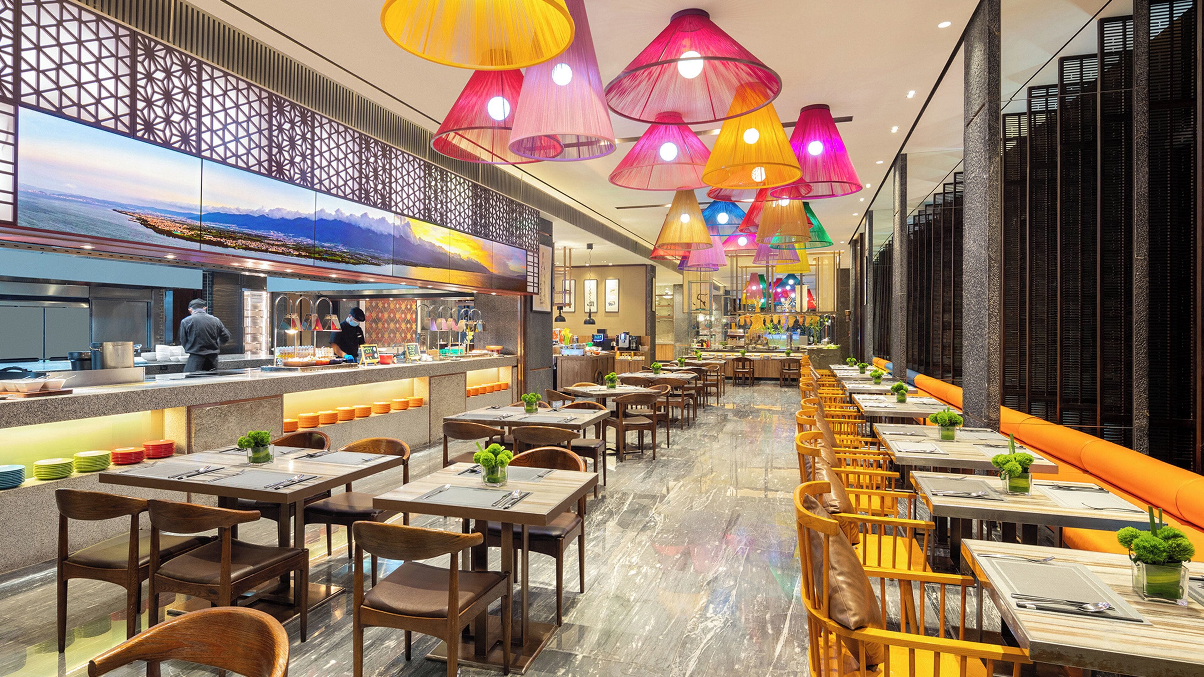 A restaurant with a long counter, multiple tables, and chairs.