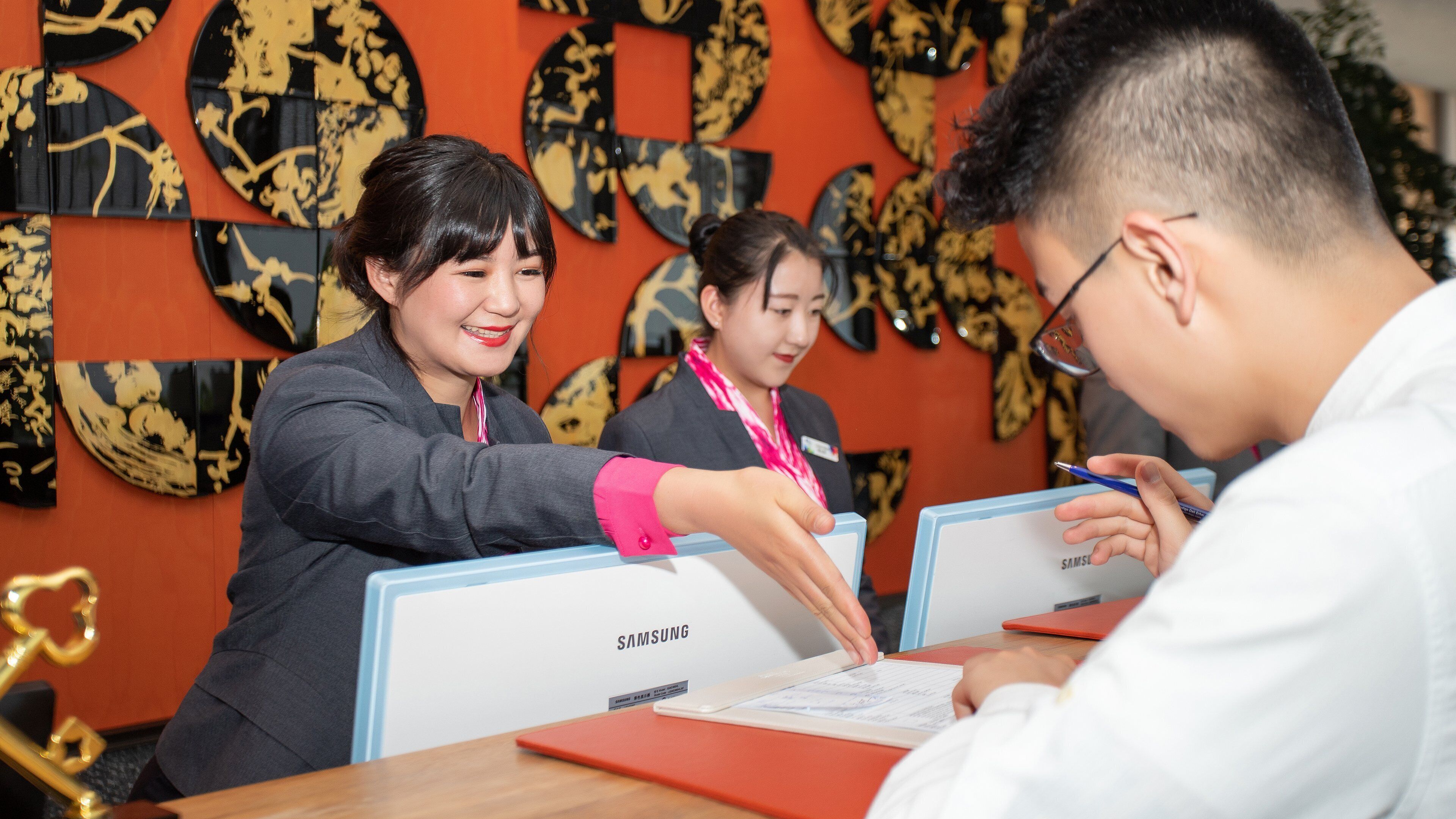 A Samsung branded office space with employees at desks, one of whom is interacting with a tablet.