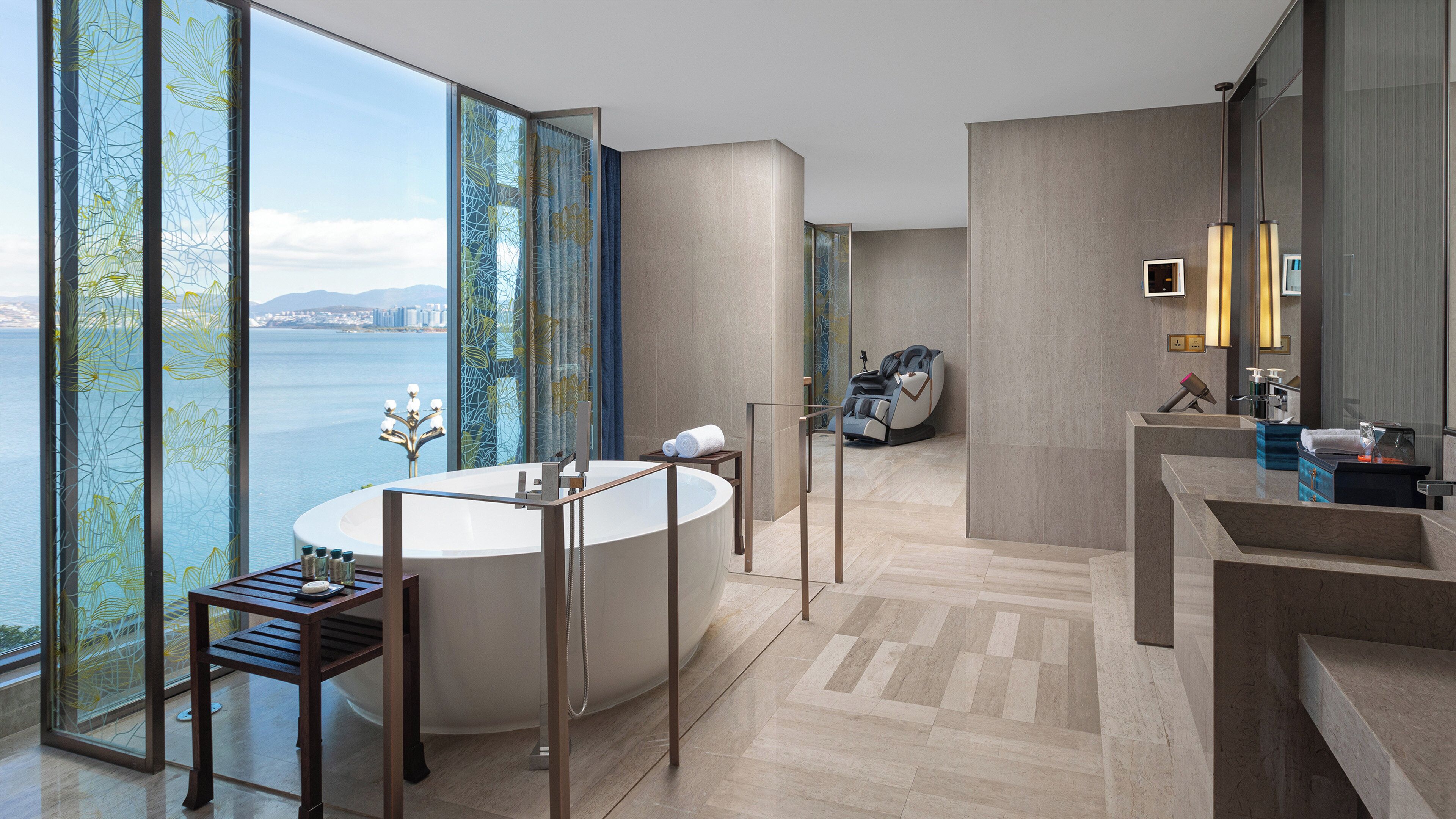 A modern bathroom with a large bathtub, a vanity, and a view of the water.