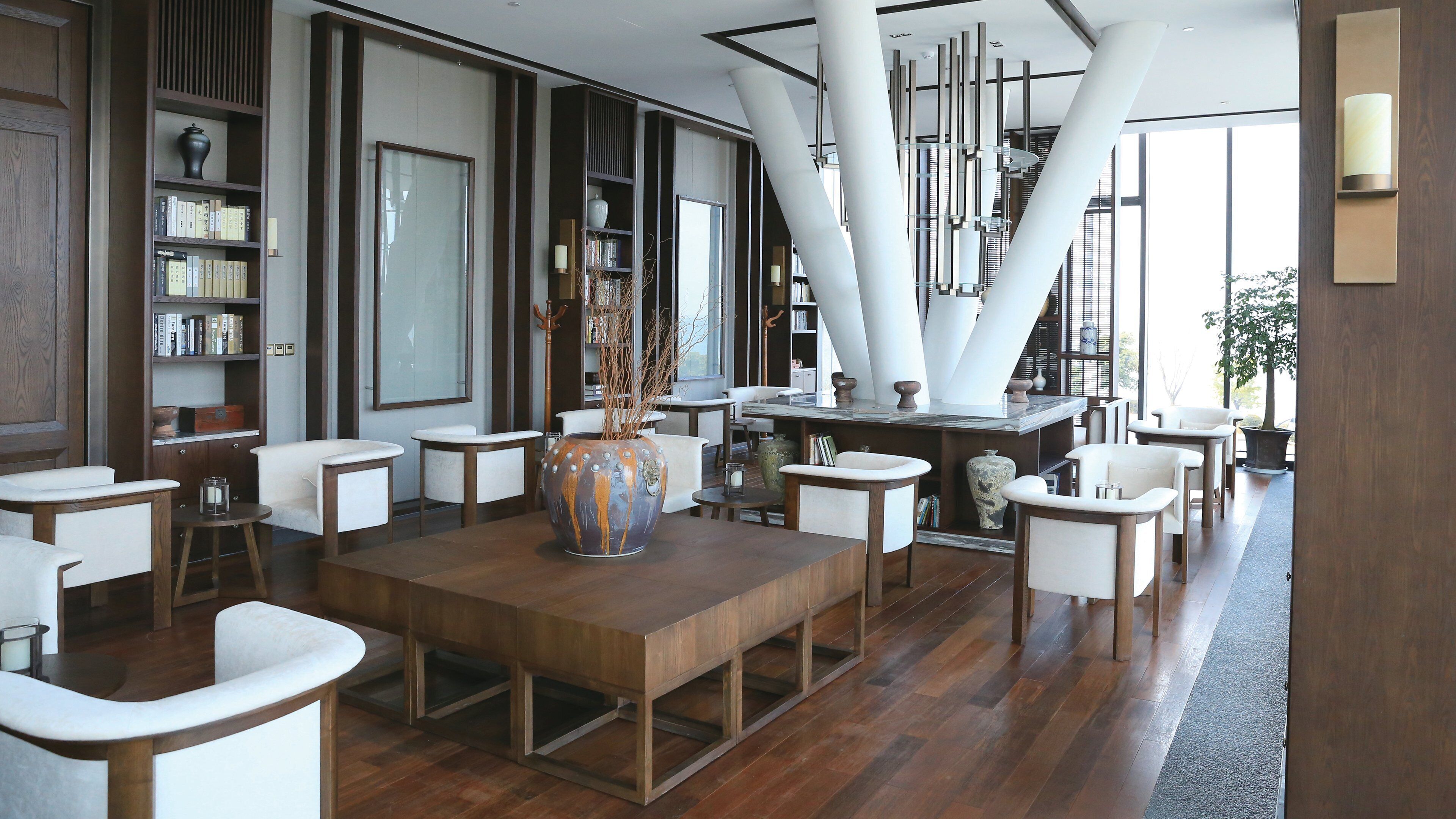 A modern interior with a wooden table, white chairs, and a large vase.