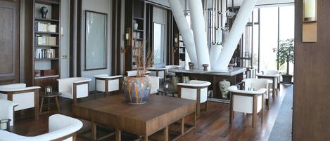A modern interior with a wooden table, white chairs, and a large vase.