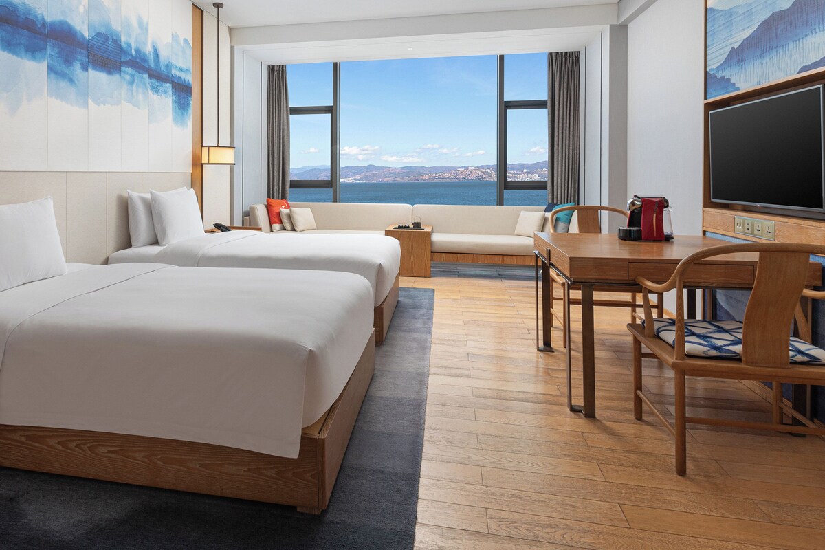 Ein Hotelzimmer mit zwei Betten, einem Esstisch und Meerblick.