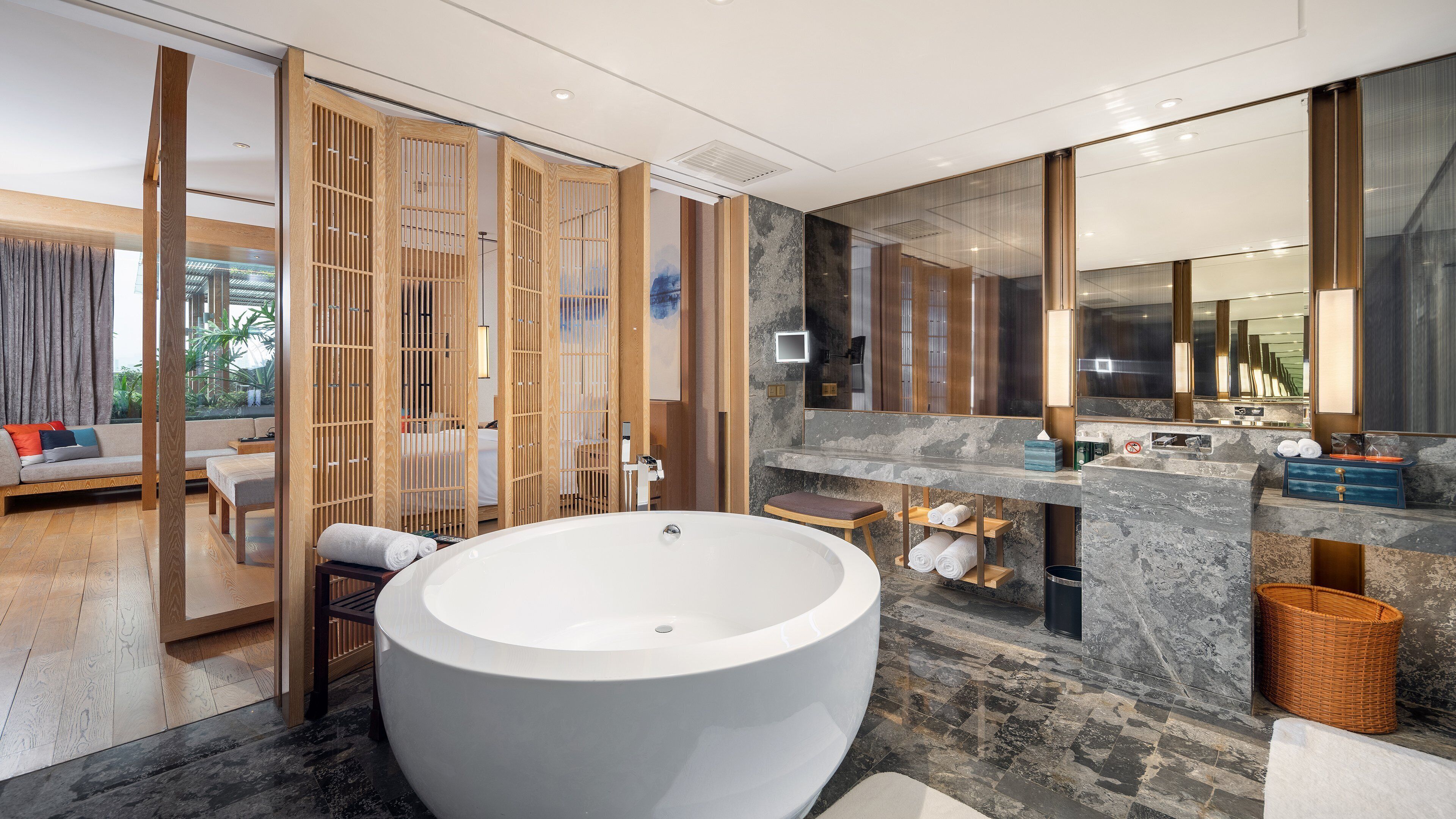 Un baño moderno con una bañera grande, una encimera de mármol y un panel de madera.