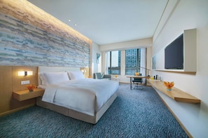 A hotel room with a large bed, a desk, a chair, a flat-screen TV, and a city view. - Holiday Inn Express Nantong Textile City by IHG (Nantong)