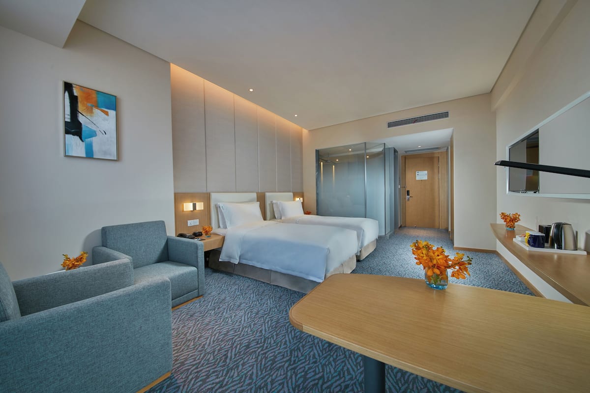 Ein Hotelzimmer mit einem großen Bett, einer Couch, einem Schreibtisch und einem Fernseher.