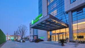 A hotel with a modern facade, large windows, and a prominent entrance with a covered walkway. - Holiday Inn Express Nantong Textile City by IHG (Nantong)