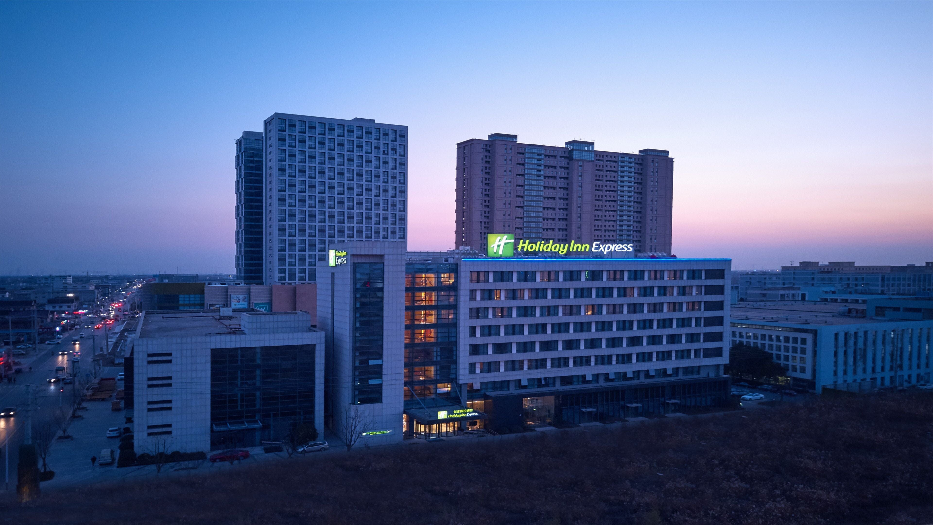 A multi-story hotel with a Holiday Inn Express sign, surrounded by other buildings and a busy street.