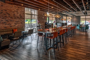 A spacious dining area with high ceilings and exposed beams, featuring a mix of bar and booth seating.