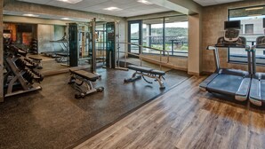 A gym with treadmills, weight machines, and a mirror wall.