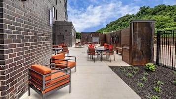 Een terras met bakstenen muren, tafels en stoelen.