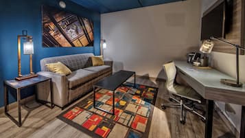Una habitación moderna con una pared azul de acento, un sofá, un escritorio y una alfombra colorida.