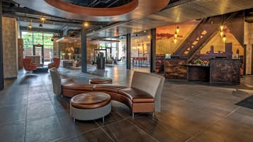 Un vestíbulo amplio con una zona de estar curvada, un mostrador de recepción y una escalera.