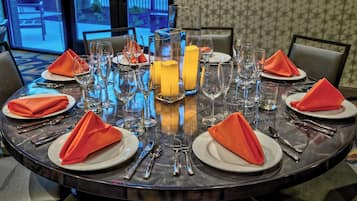 A round dining table set for four with clear glassware, plates, and cutlery.
