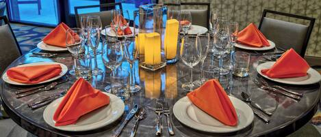 A round dining table set for four with clear glassware, plates, and cutlery.
