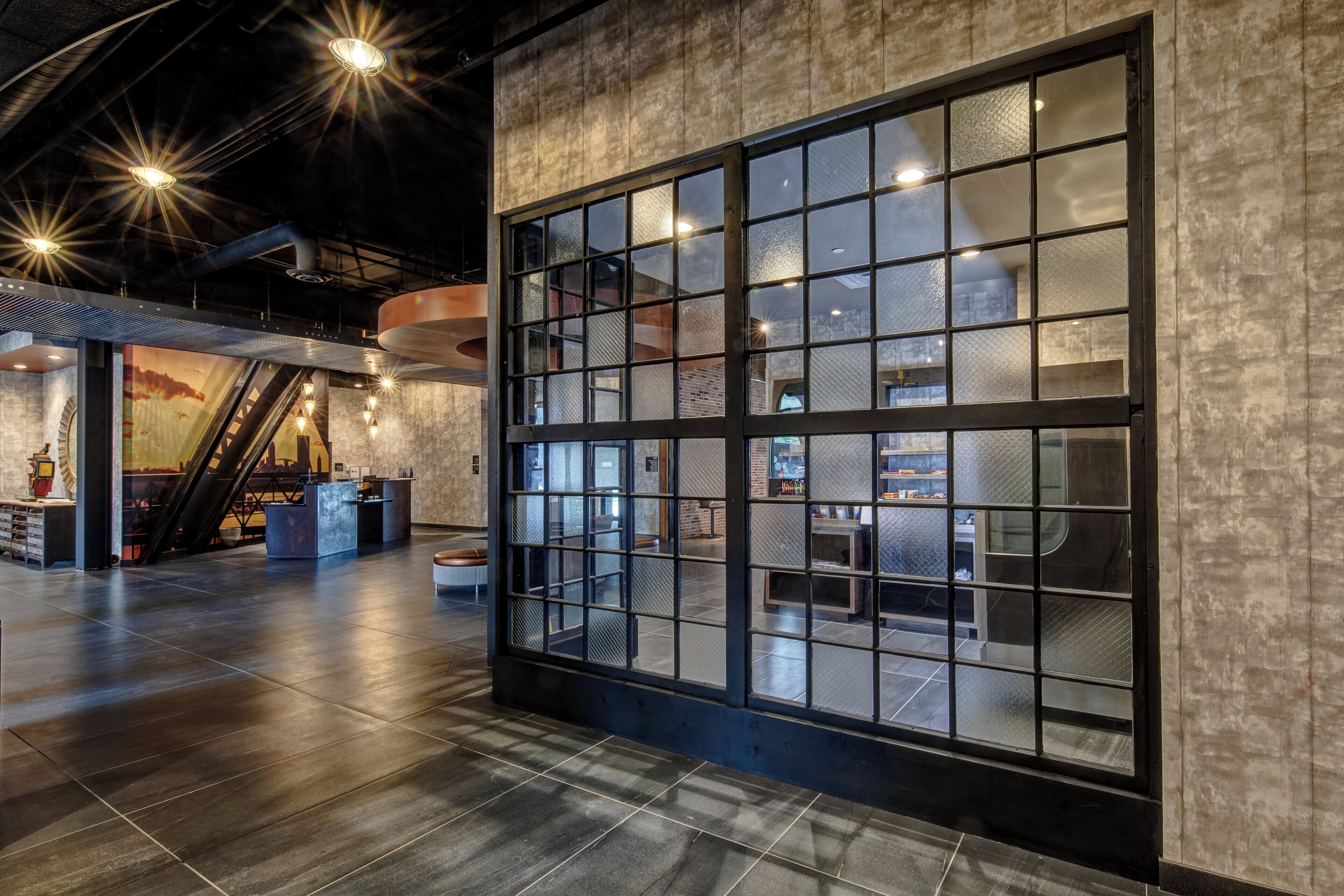 A spacious lobby with a large glass wall, a reception desk, and a staircase leading to upper levels.