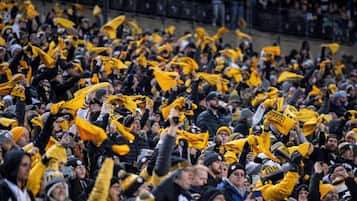 A crowded indoor space with numerous people, some wearing yellow and black attire.
