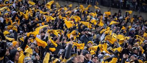 A crowded indoor space with numerous people, some wearing yellow and black attire.