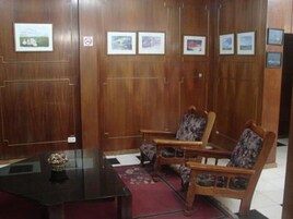 Una habitación con paneles de madera, un escritorio con un florero y dos sillas con tapicería floral.