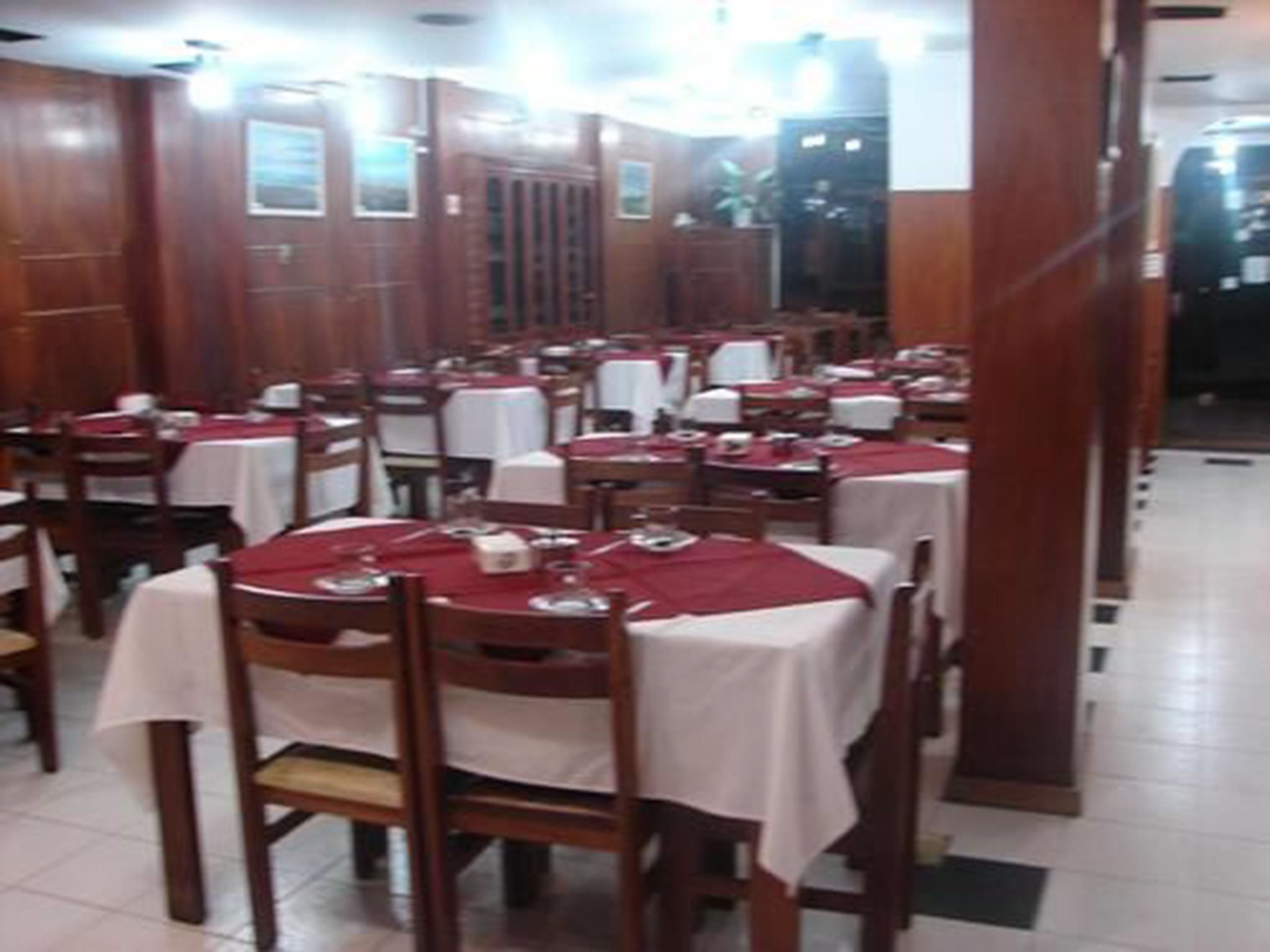 A restaurant with multiple tables and chairs, arranged in rows.