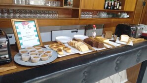 A buffet counter with various baked goods, including muffins, bread, and pastries. - Cheltum Hotel (Trelew)
