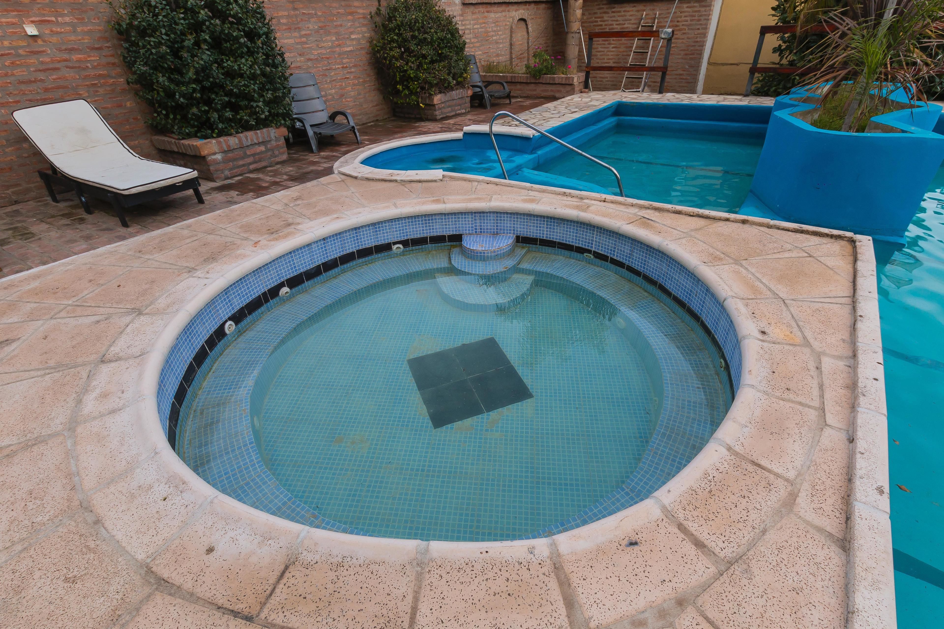Un jacuzzi circular con borde de azulejos, rodeado por un patio de ladrillo.