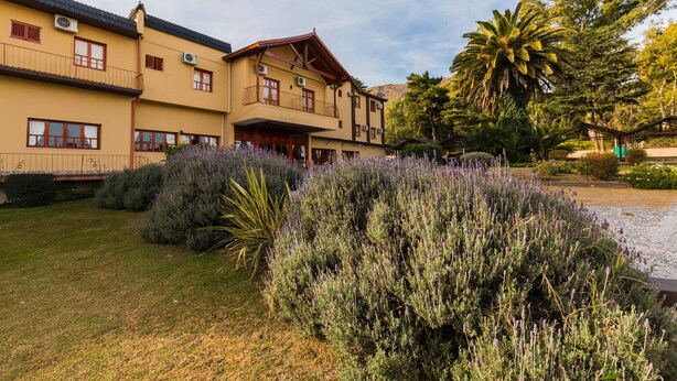 Un hotel con estructura de dos pisos, balcones y un jardín con plantas de lavanda.