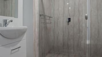 Un baño moderno con ducha de vidrio, lavabo blanco y un inodoro.
