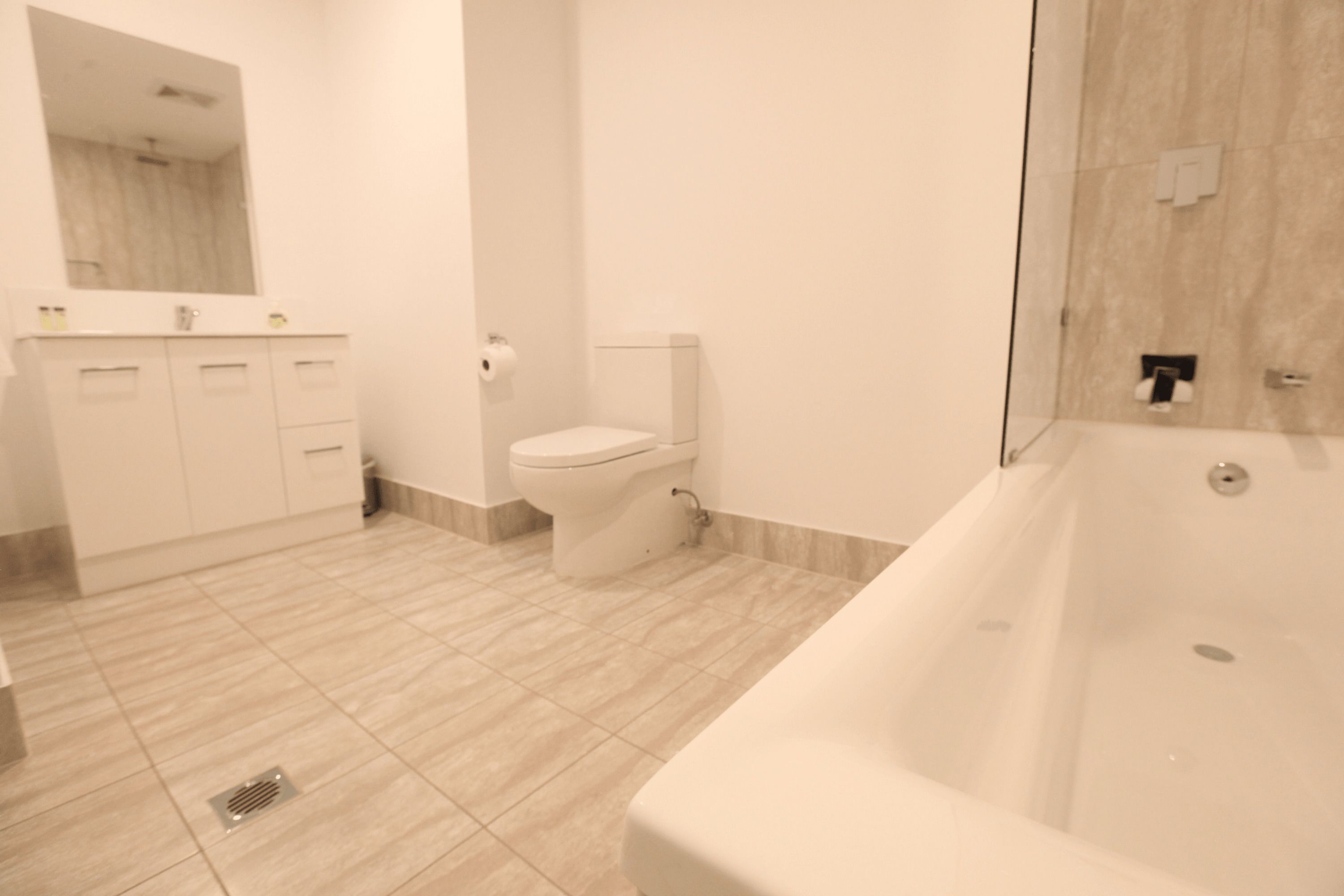 A modern bathroom with a bathtub, toilet, and vanity.