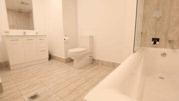 A modern bathroom with a bathtub, toilet, and vanity.