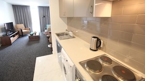 A modern kitchen with a built-in oven, a coffee maker, and a sink. - The Palms Apartments (Kent Town)