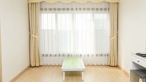 A room with a wooden floor, a white bench, and a window with sheer curtains. - Daebudo Hotel Marina (Ansan)