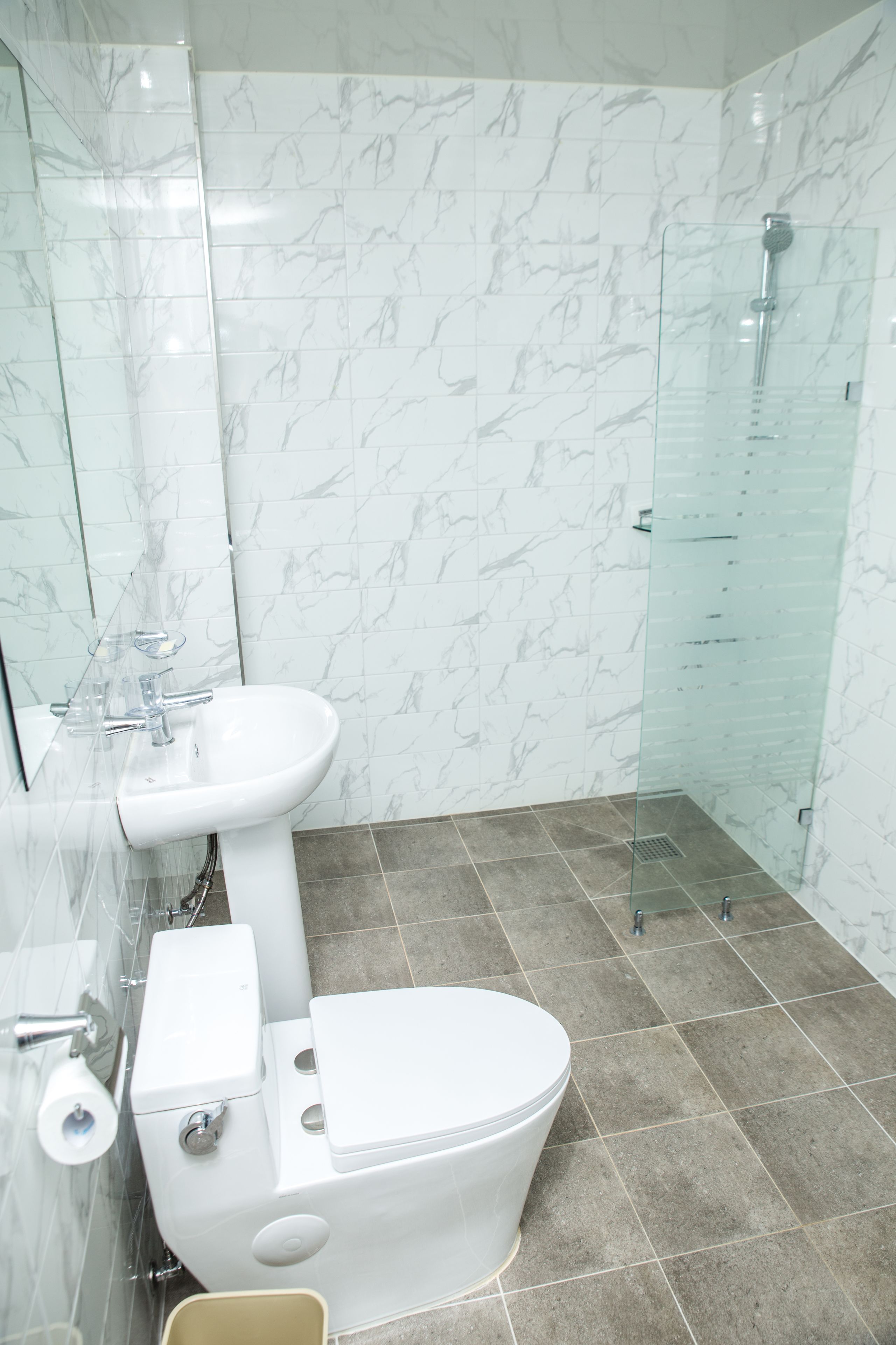 A modern bathroom with a white toilet, sink, and glass shower enclosure.