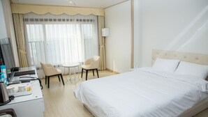 A hotel room with a large bed, a desk with a computer, a chair, and a small table. - Daebudo Hotel Marina (Ansan)