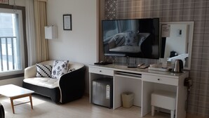 A modern living room with a sofa, a TV, a desk, and a small fridge. - Daebudo Hotel Marina (Ansan)