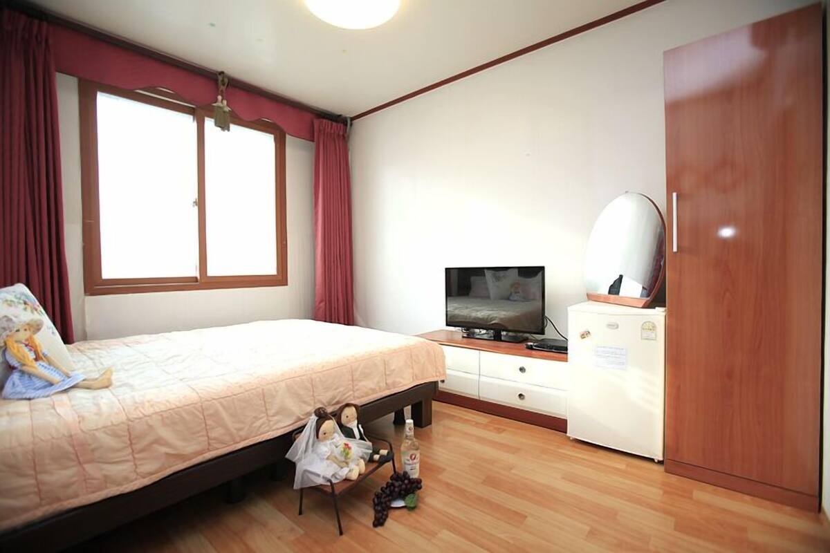 A bedroom with a bed, a television, a dresser, and a wardrobe.