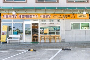 Un restaurant avec une enseigne jaune, des tables en plein air et la possibilité de commander à emporter.