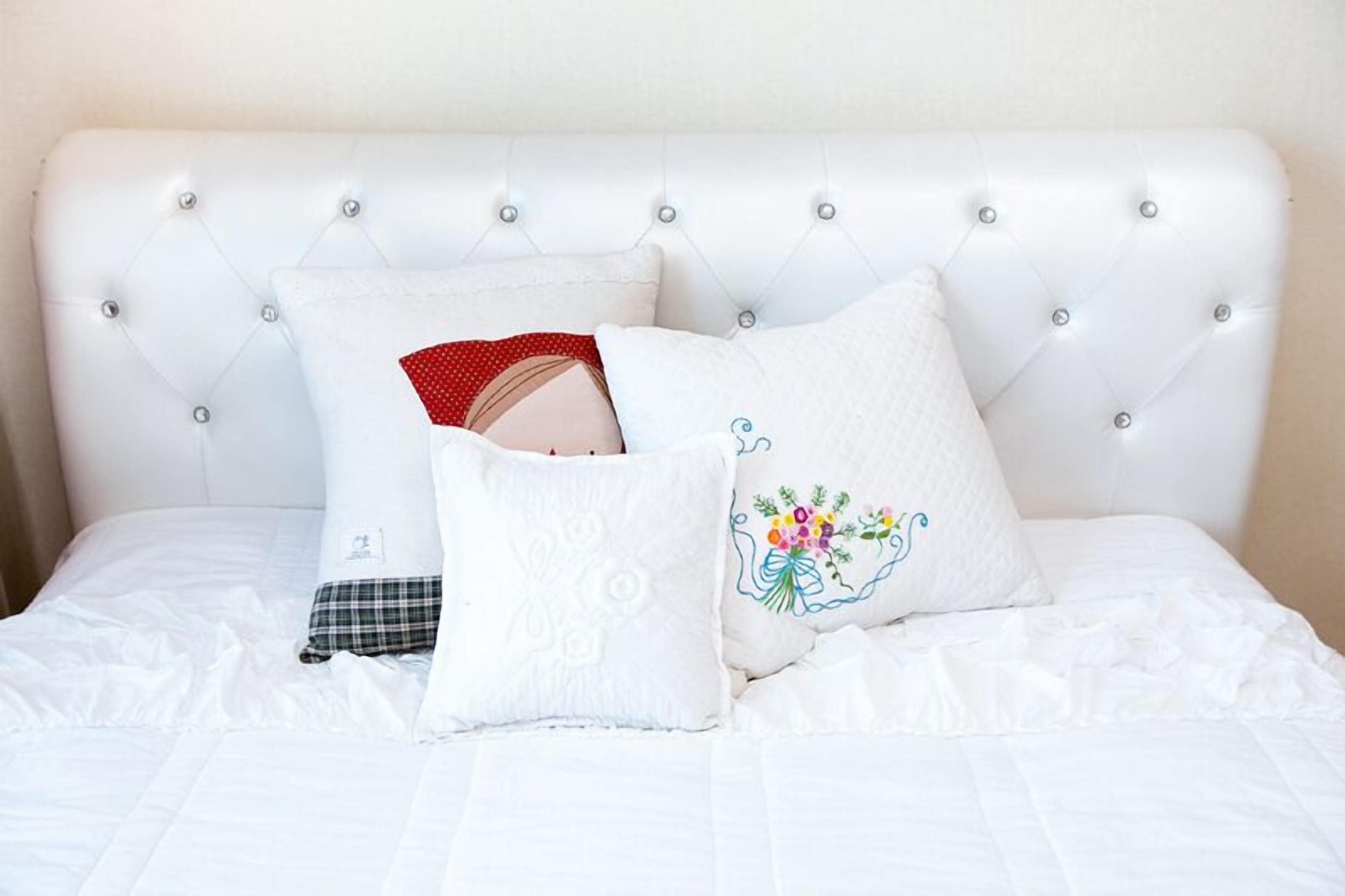 A bed with a tufted headboard and three pillows.