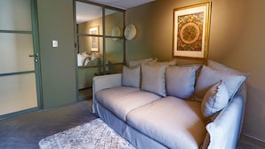 A living room with a sofa, a patterned rug, a wall-mounted artwork, and a sliding door. - Aikia City CDMX (Mexico City)