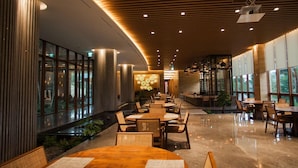 A modern restaurant with a long counter, wooden chairs, and large windows offering a view of the outdoors. - Hotel Maestro (Anseong)