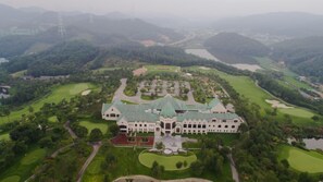 A large, historic building with a central courtyard, surrounded by well-manicured lawns and golf courses.