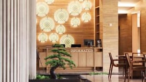 A hotel lobby with a reception desk, a small indoor garden, and a dining area. - Hotel Maestro (Anseong)