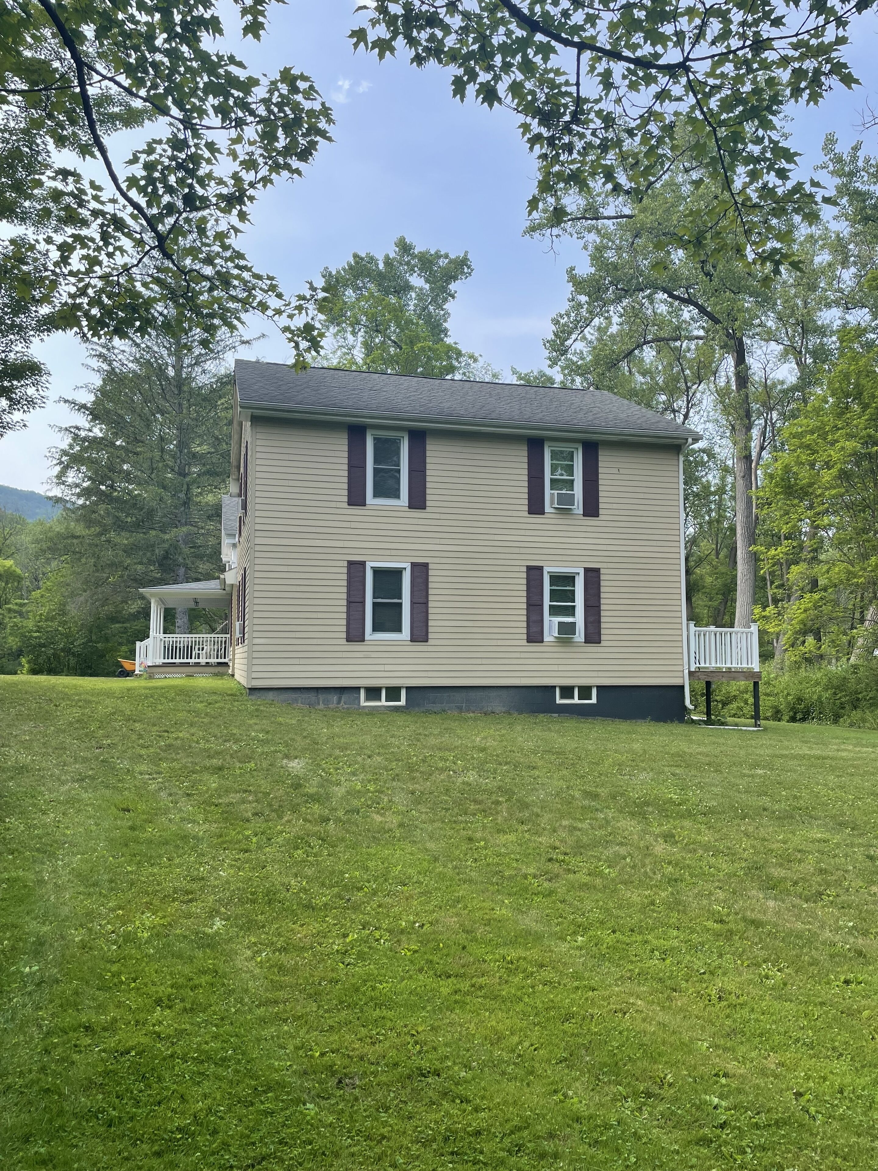 A two-story house with a front porch and a small deck.